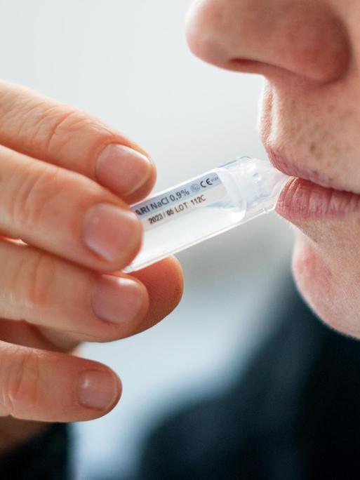 Jemand führt einen Selbsttest mittels Gurgelmethode durch