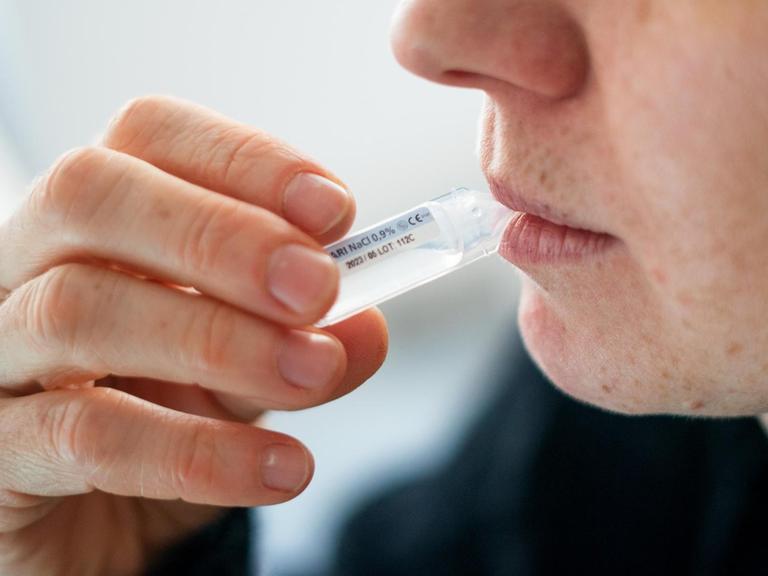 Jemand führt einen Selbsttest mittels Gurgelmethode durch