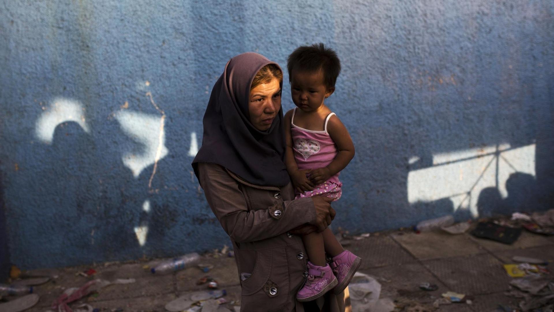 Eine Frau auf Lesbos hält ihr Kind auf dem Arm und wartet auf ihre Registrierung.