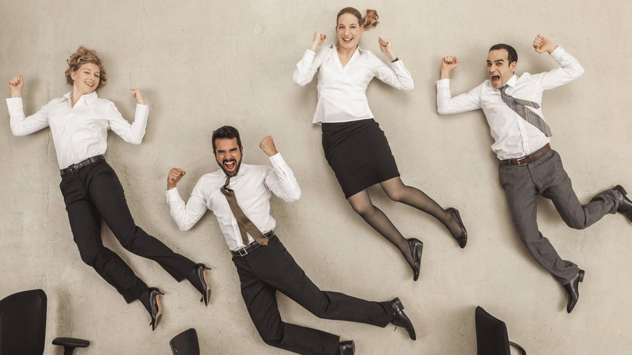 Menschen in Businesskleidung liegen auf dem Rücken, als würden sie durchs Büro springen