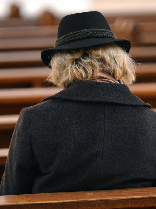 Eine Frau sitzt auf einer Kirchenbank