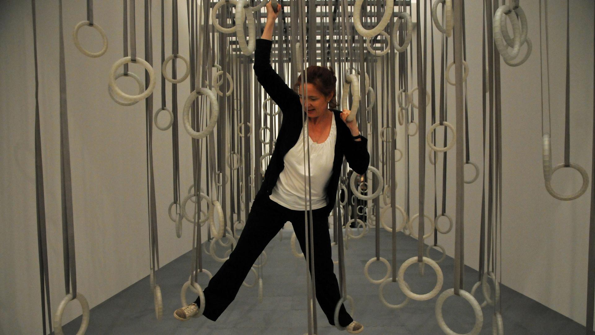 Eine Besucherin bewegt sich im Düsseldorfer Museum Kunstpalast bei der Ausstellung "MOVE - Kunst und Tanz seit den 60ern" in dem choreographischen Objekt: Platikringe und Gurtbänder "The Fact of Matter (Die Tatsache der Sachen) des armerikanischen Künstlers William Fortsythe.