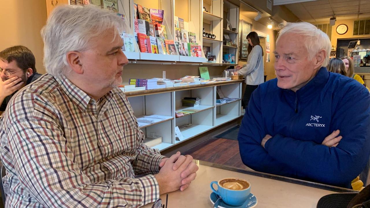 Gordon Fischer und Jim Leach diskutieren an einem Tisch im Café.