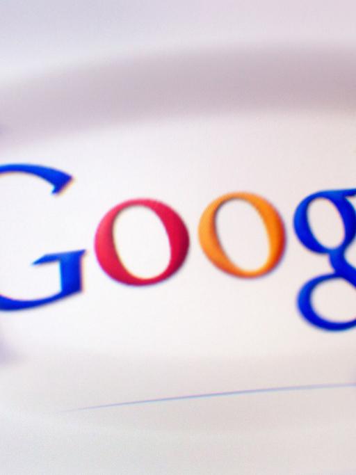 Das Google-Logo ist durch ein Brillenglas auf einem Bildschirm zu sehen.