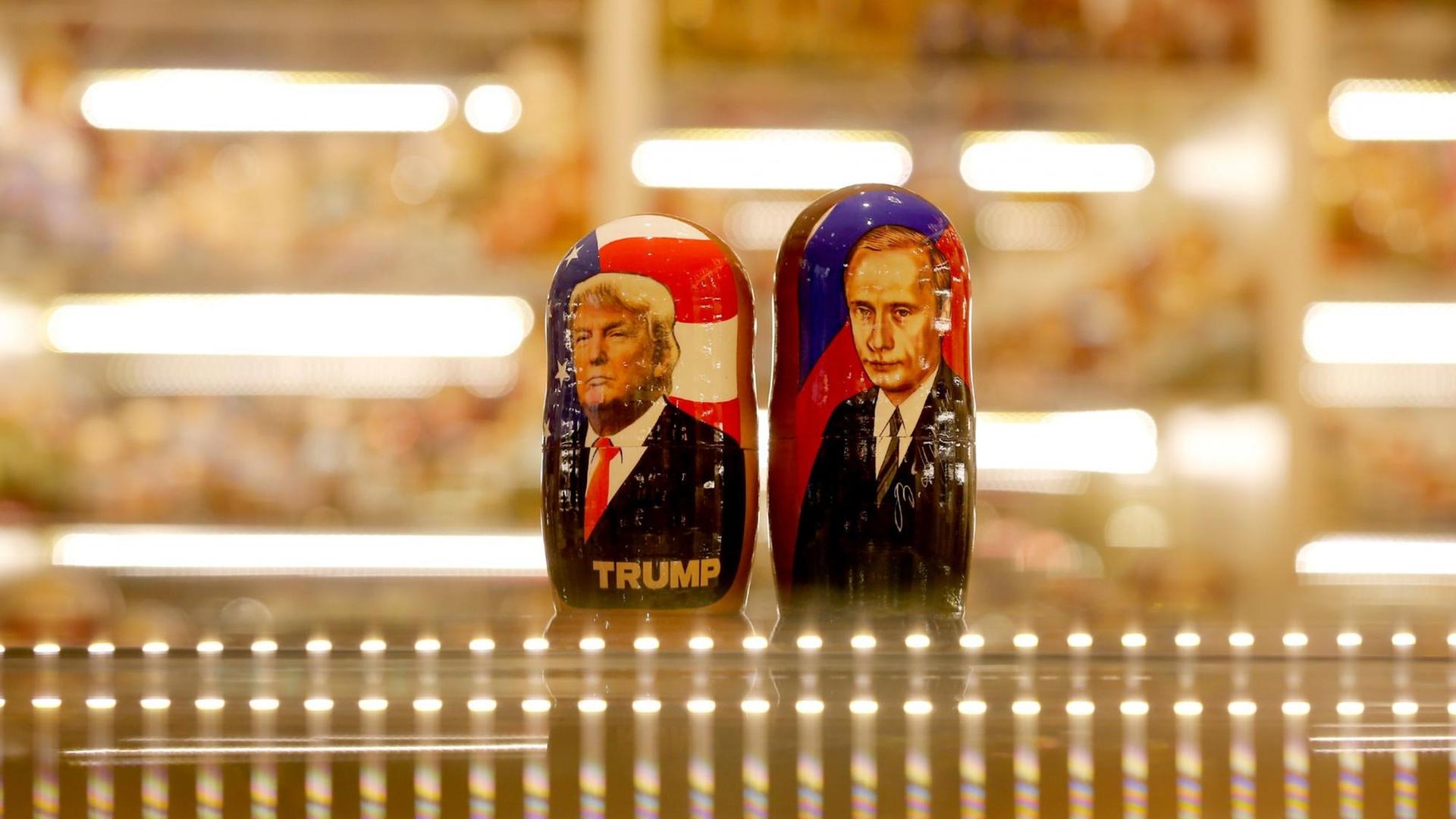 Zwei bemalte Matroschka-Puppen von Wladimir Putin und Donald Trump auf der gläsernen Theke eines Souvenirgeschäft.