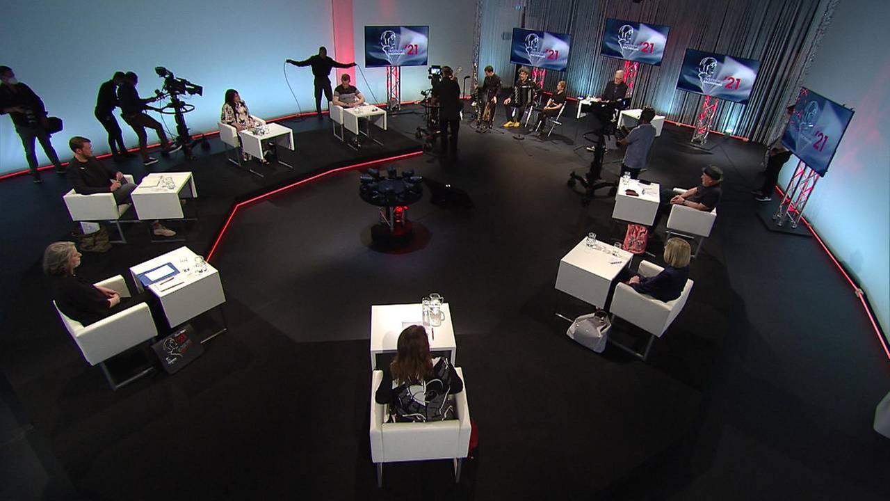 Blick in das Fernsehstudio, in dem die sieben Jurymitglieder des Bachmannpreises im Kreis sitzen.