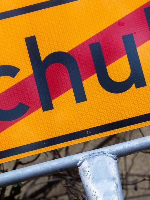 Ein Schild mit einem durchgestrichenen Schriftzug "Schule"