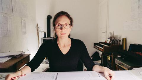Rebecca Saunders sitzt in einem Arbeitszimmer an einem Schreibtisch