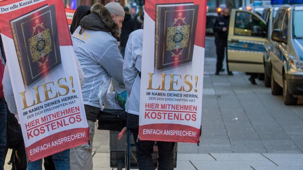 Mit einem Plakaten auf dem Rücken versuchen Teilnehmer der von Salafisten organisierten Koran-Verteilaktion "Lies" auf der Zeil in Frankfurt am Main die Aufmerksamkeit auf sich zu ziehen.