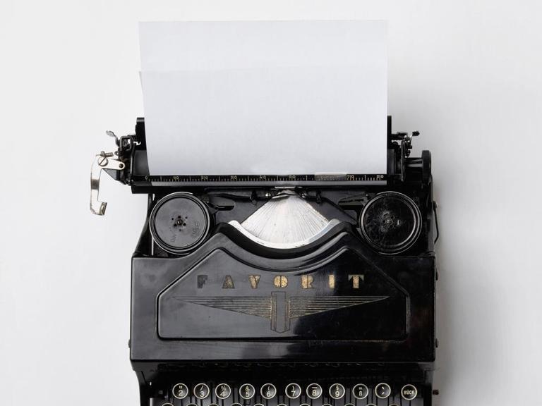 Eine historische Schreibmaschine in die ein weißes Blatt eingespannt ist.