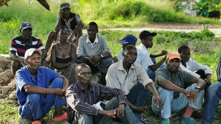 Ehemalige DDR-Vertragsarbeiter protestieren am Boden sitzend in Mosambik.