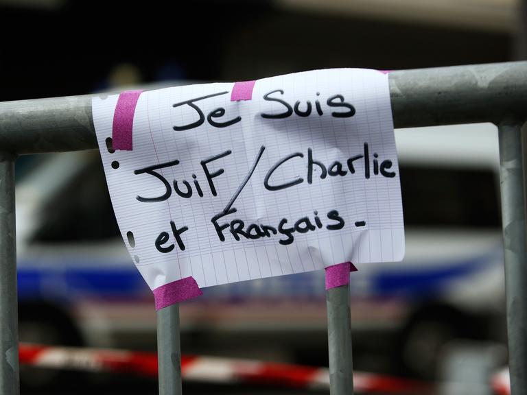 Ein Schild mit der Aufschrift "Je suis Juif, Charlie et Francais" - "Ich bin Jude, Charlie und Franzose" auf einer Sicherheitsabsperrung am 10.1.2014, einen Tag, nachdem vier Juden in einem koscheren Supermarkt von Paris ermordet wurden.