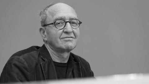 Ein älterer Mann mit Brille schaut in die Kamera.