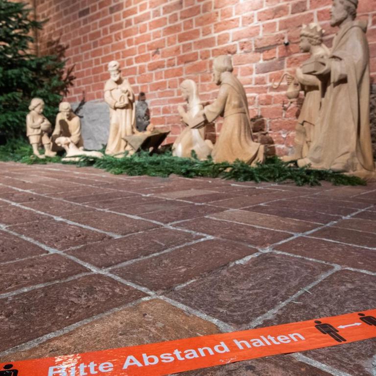Klebeband mit der Aufschrift "Bitte Abstand halten" klebt vor einer Weihnachtskrippe in der Marktkirche Hannover.