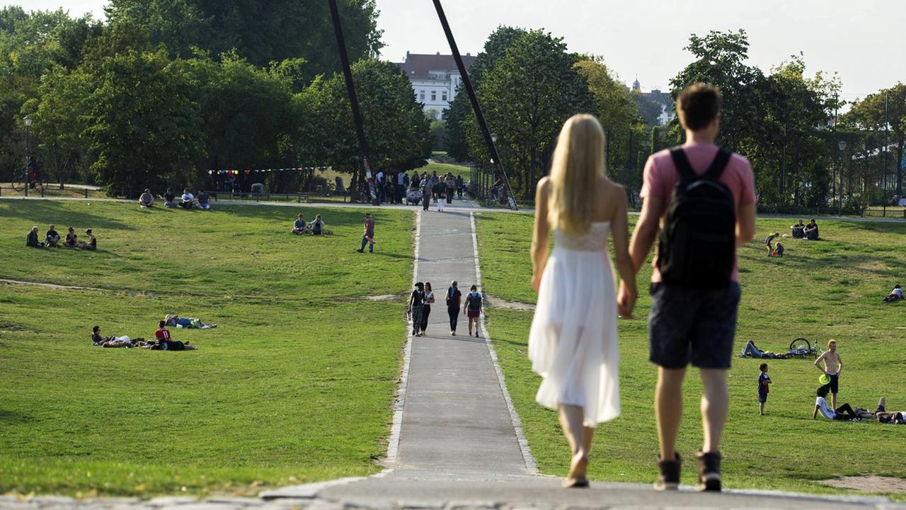 Ein Paar läuft Händchen haltend in der Abendsonne durch den Görlitzer Park in Berlin-Kreuzberg