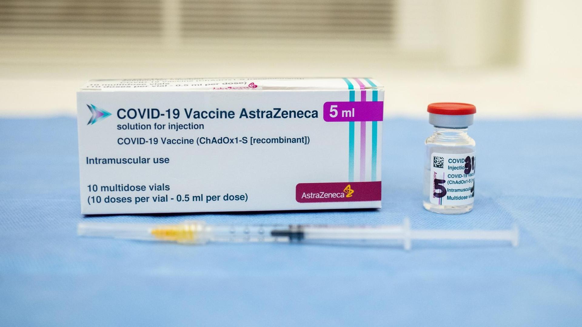 Die Verpackung des Corona-Impfstoffs von Astrazeneca. Daneben eine Ampulle und davor eine Spritze, mit der der Impfstoff verabreicht werden kann.