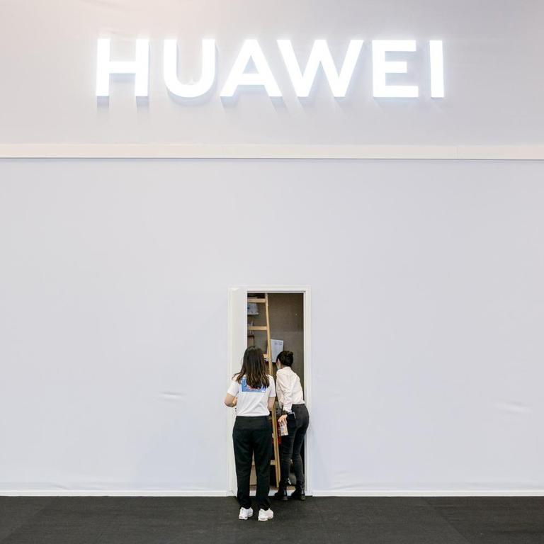 Zwei Mitarbeiter des Technologieunternehmen Huawei in der Internationalen Funkausstellung (IFA) stehen vor einem Seiteneingang des Standes. 