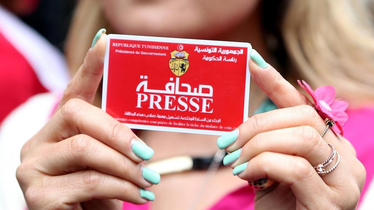 A Tunisian journalist poses with her Tunisian press card during a protest in front of the Interior Ministry to denounce the violations against journalists and media professionals in Tunis, Tunisia, 03 March 2014. The Arab Network for Human Rights Information (ANHRI) on 03 March condemned the growing violations against journalists and media professionals on the job by Tunisian authorities.