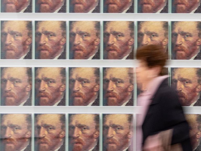 Eine Besucherin geht in der Ausstellung "Making van Gogh" an Katalogen mit einem Selbstporträt des Malers vorbei.