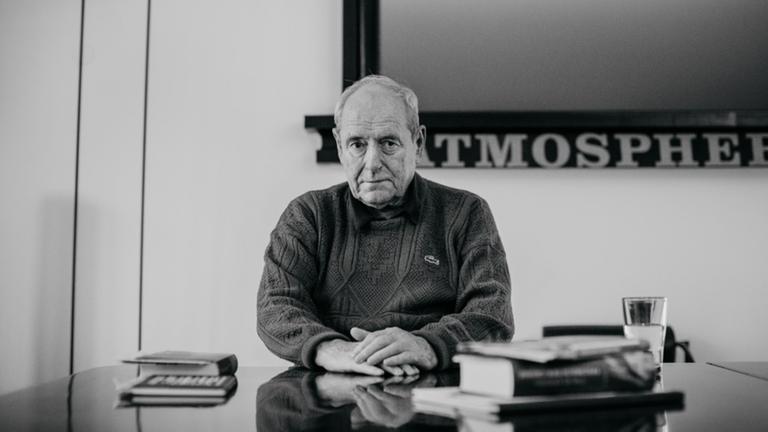 Der Kunstsammler Harald Falckenberg sitzt an einem Schreibtisch mit Büchern