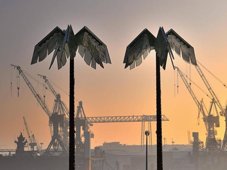Zwei künstliche Palmen stehen im rötlichen Abendlicht am Hamburger Hafen.
