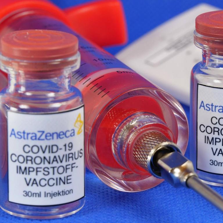 Zwei Phiolen mit dem Coronaserum-Impfstoff von AstraZeneca. Dazwischen liegt eine Spritze.