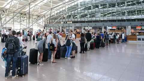 Fluggäste stehen auf dem Hamburger Flughafen am Check-in an.