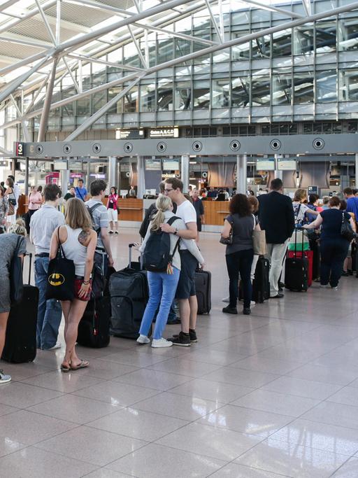 Fluggäste stehen auf dem Hamburger Flughafen am Check-in an.