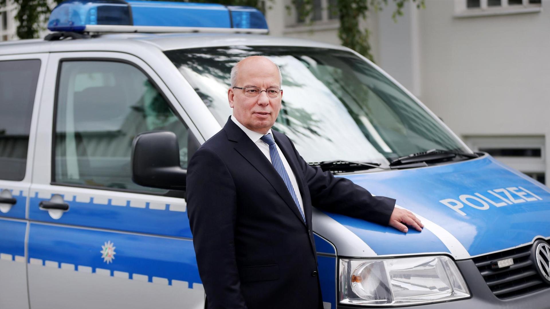 Rainer Wendt steht bei Dreharbeiten für eine Fernsehserie vor einem Streifenwagen.