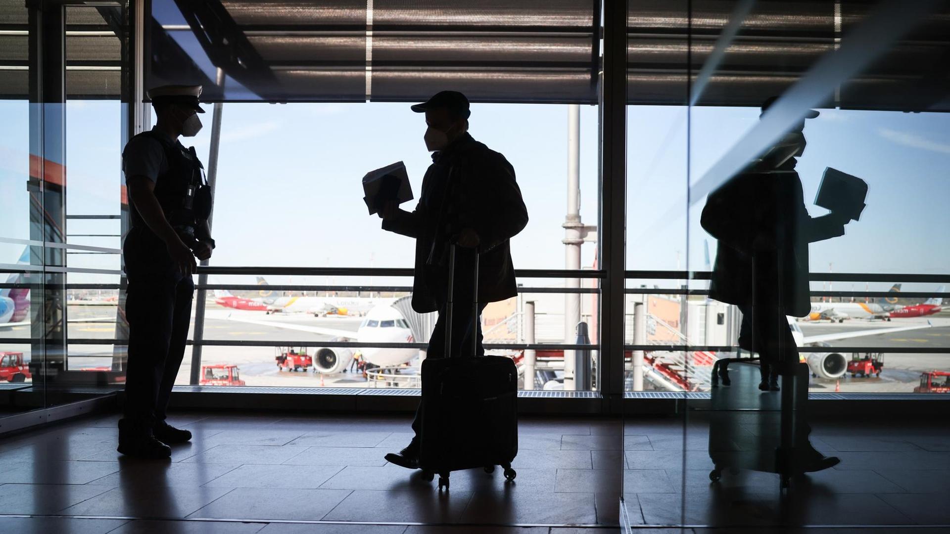 Beamte der Bundespolizei kontrollieren im  Flughafen Hamburg Passagiere eines ankommenden Flugzeugs aus Zürich. Seit Ende März müssen alle aus dem Ausland einreisenden Fluggäste einen negativen Corona-Test nachweisen können.