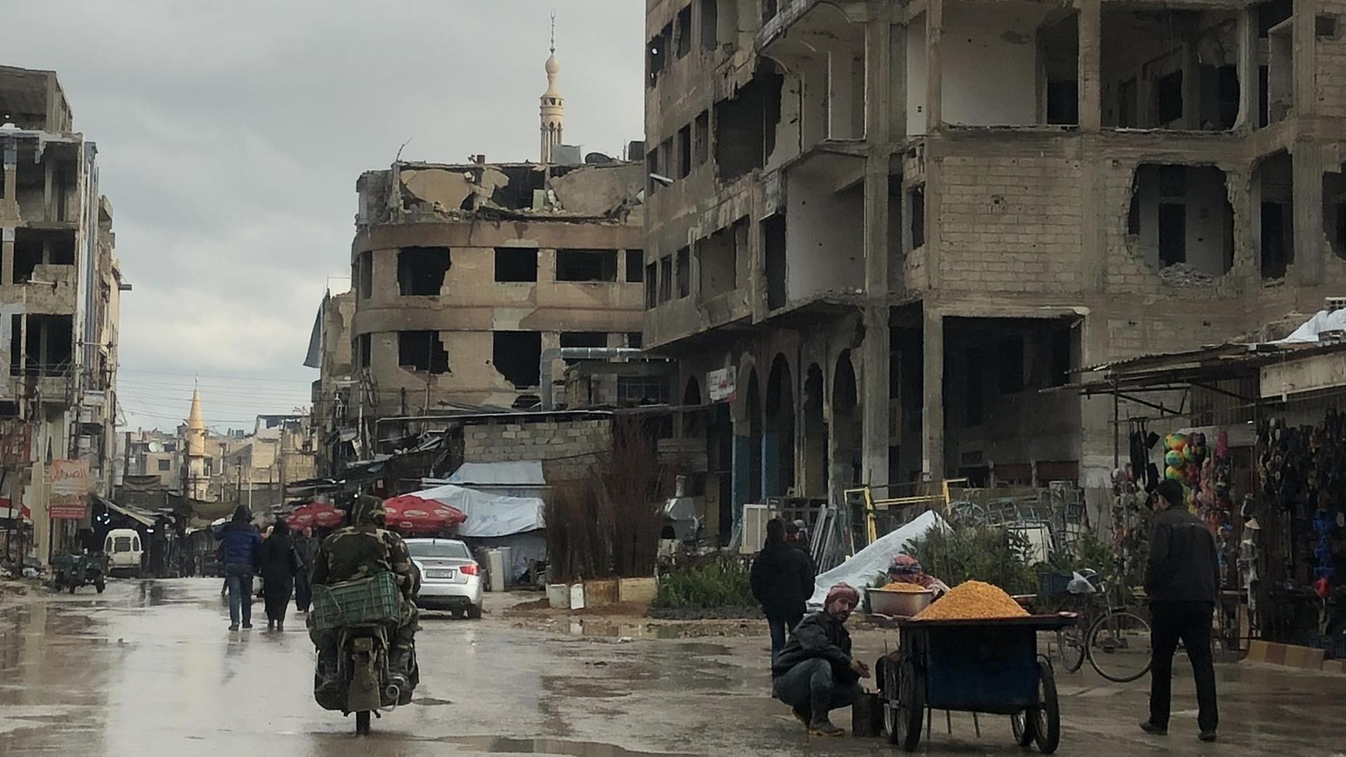 Motorradfahrer vor Häuserruinen in der syrischen Stadt Duma. Motorradfahrer vor Häuserruinen in der syrischen Stadt Duma.