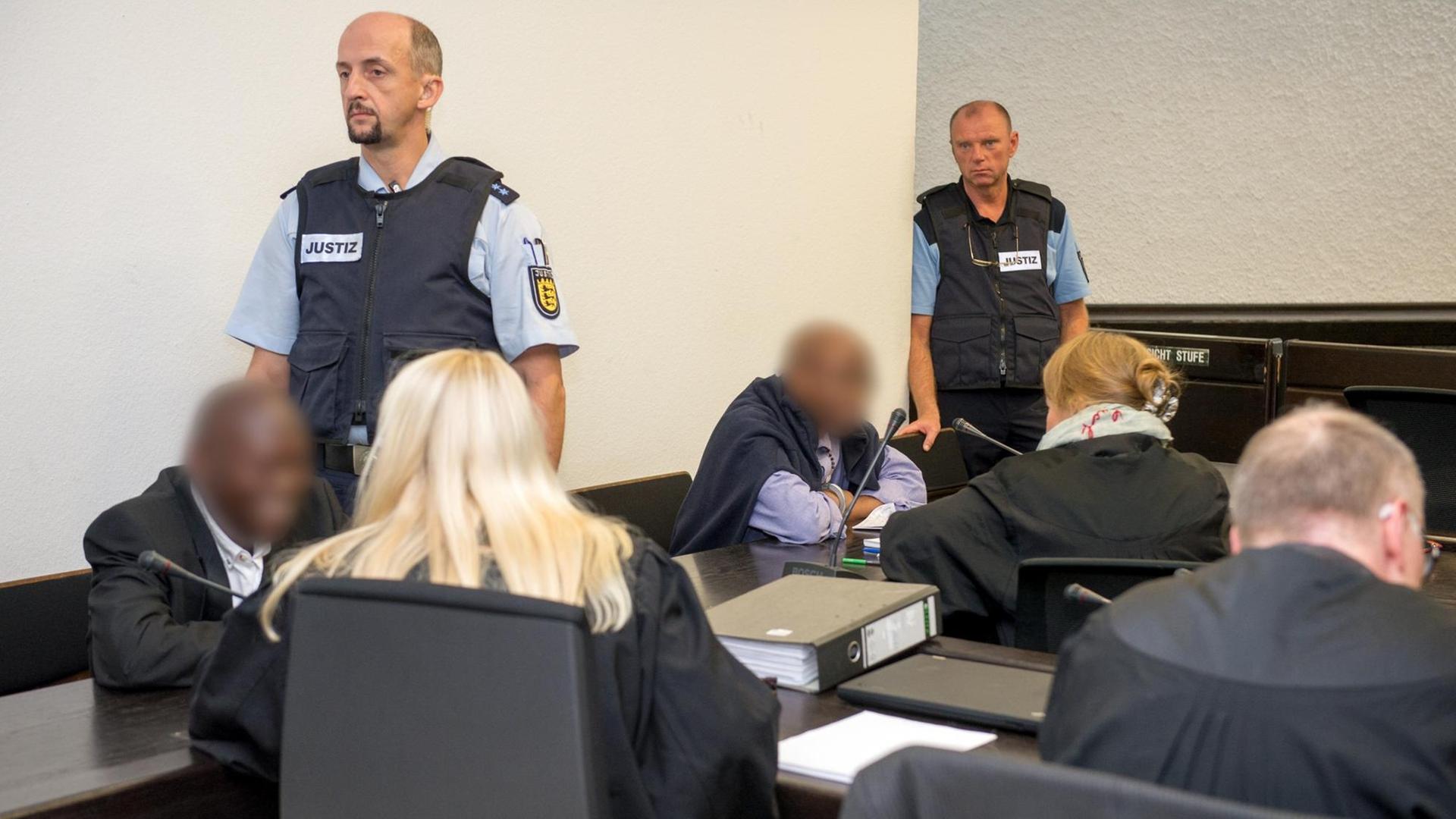 Die Angeklagten Straton M. (l) und Ignace M. (4.v.l.) sitzen im Gerichtssaal des Oberlandesgerichts in Stuttgart (Baden-Württemberg) vor der Urteilsverkündung in der Anklagebank neben ihren Anwälten.