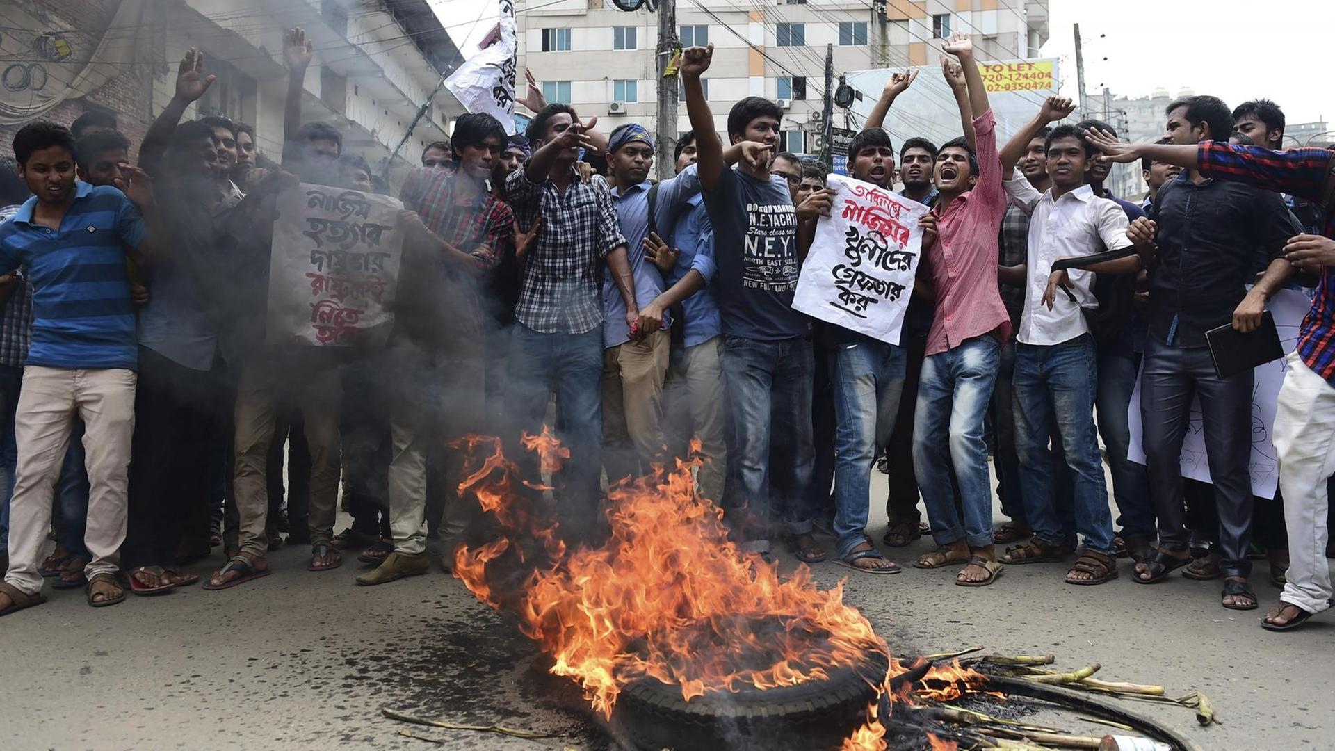 Studenten aus Bangladesch protestierten vor brennenden Auto und Fahrradreifen.