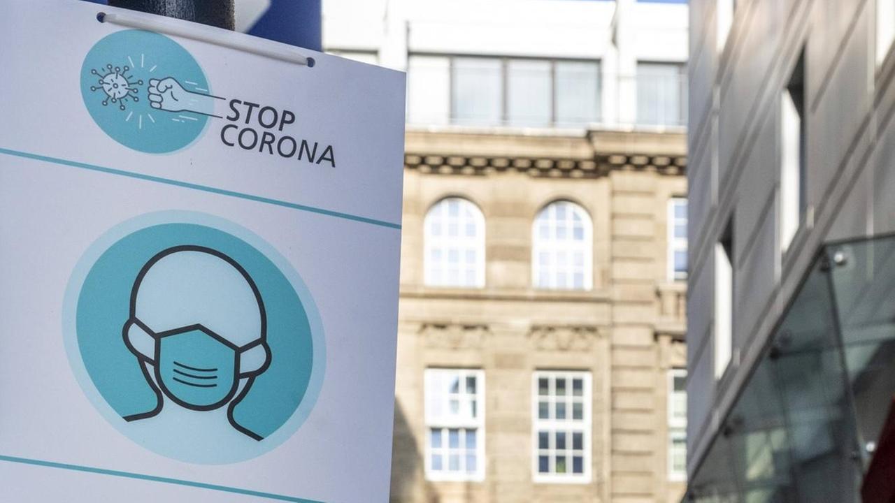 Ein Schild mit der Aufschrift "Stop Corona" und einem Menschen mit Maske darauf