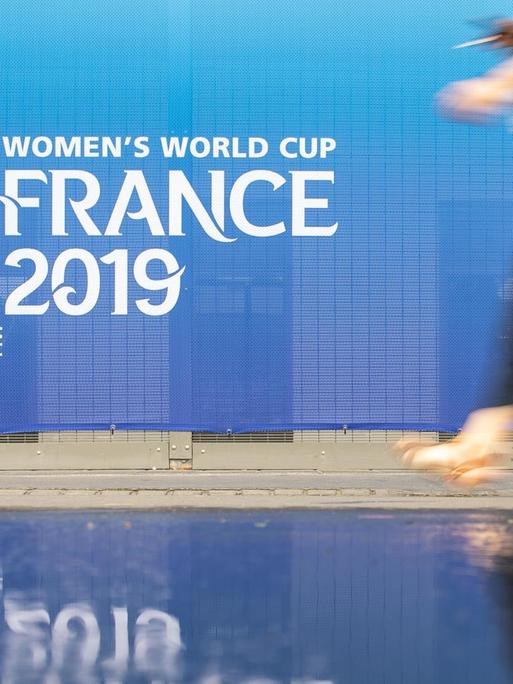 Eine Frau geht an einem Banner für die Fußball-Weltmeisterschaft der Frauen in Frankreich 2019 am Stadion Roazhon Park vorbei.