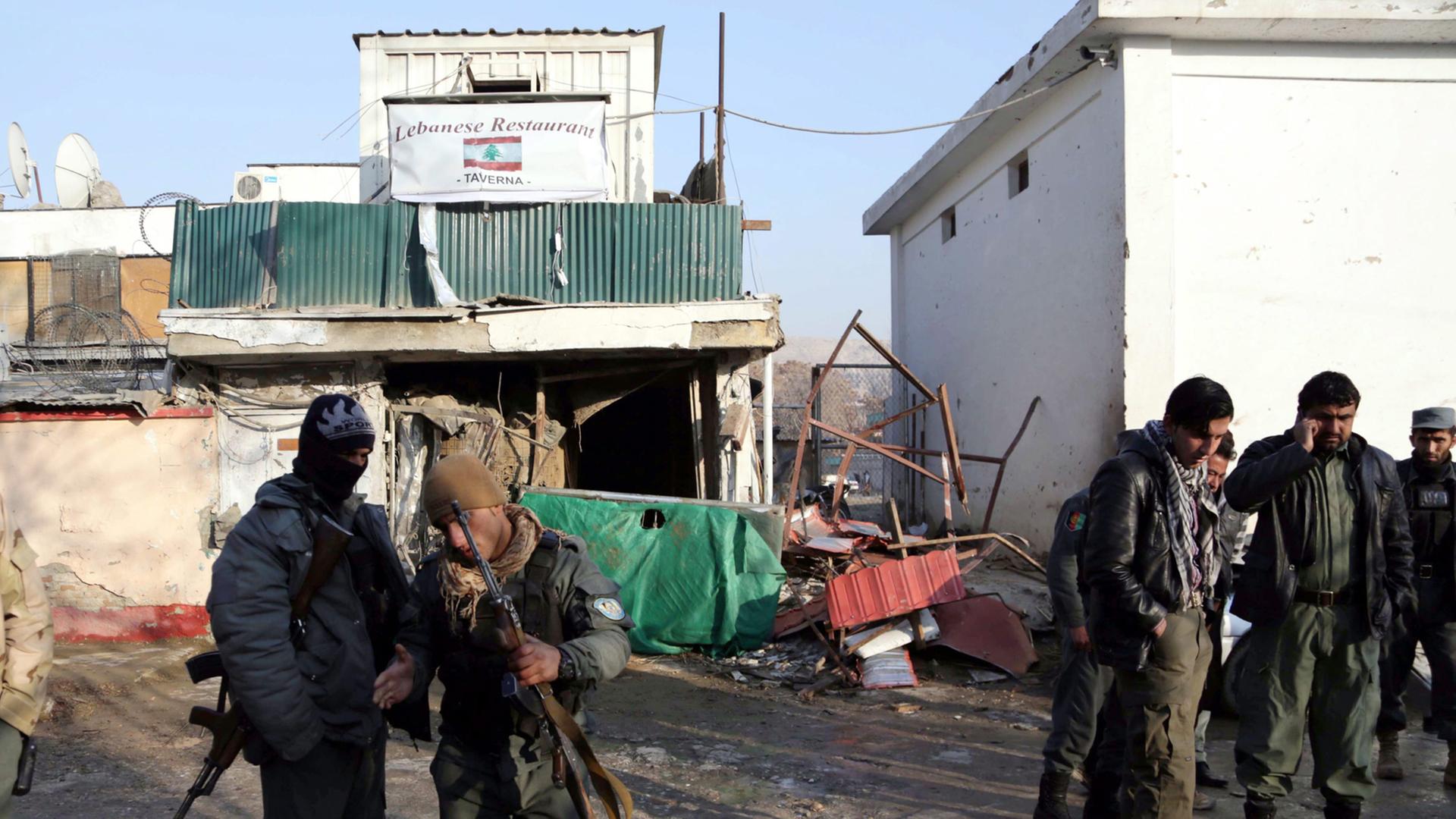 Vor einem stark beschädigten Gebäude stehen afghanische Sicherheitskräfte.
