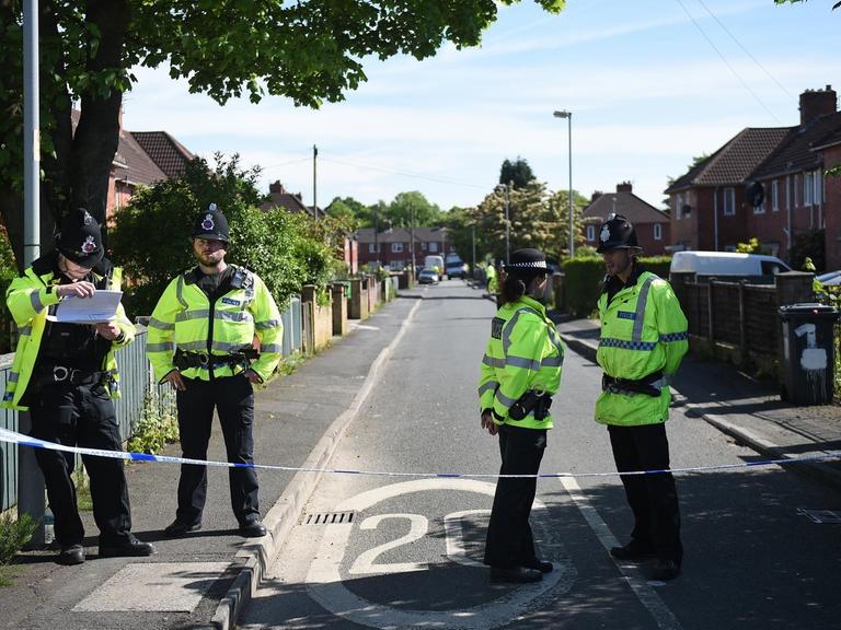 Polizisten im Stadtteil Fallowfield in Manchester an einer abgesperrten Straße, an der ein Haus durchsucht wurde.