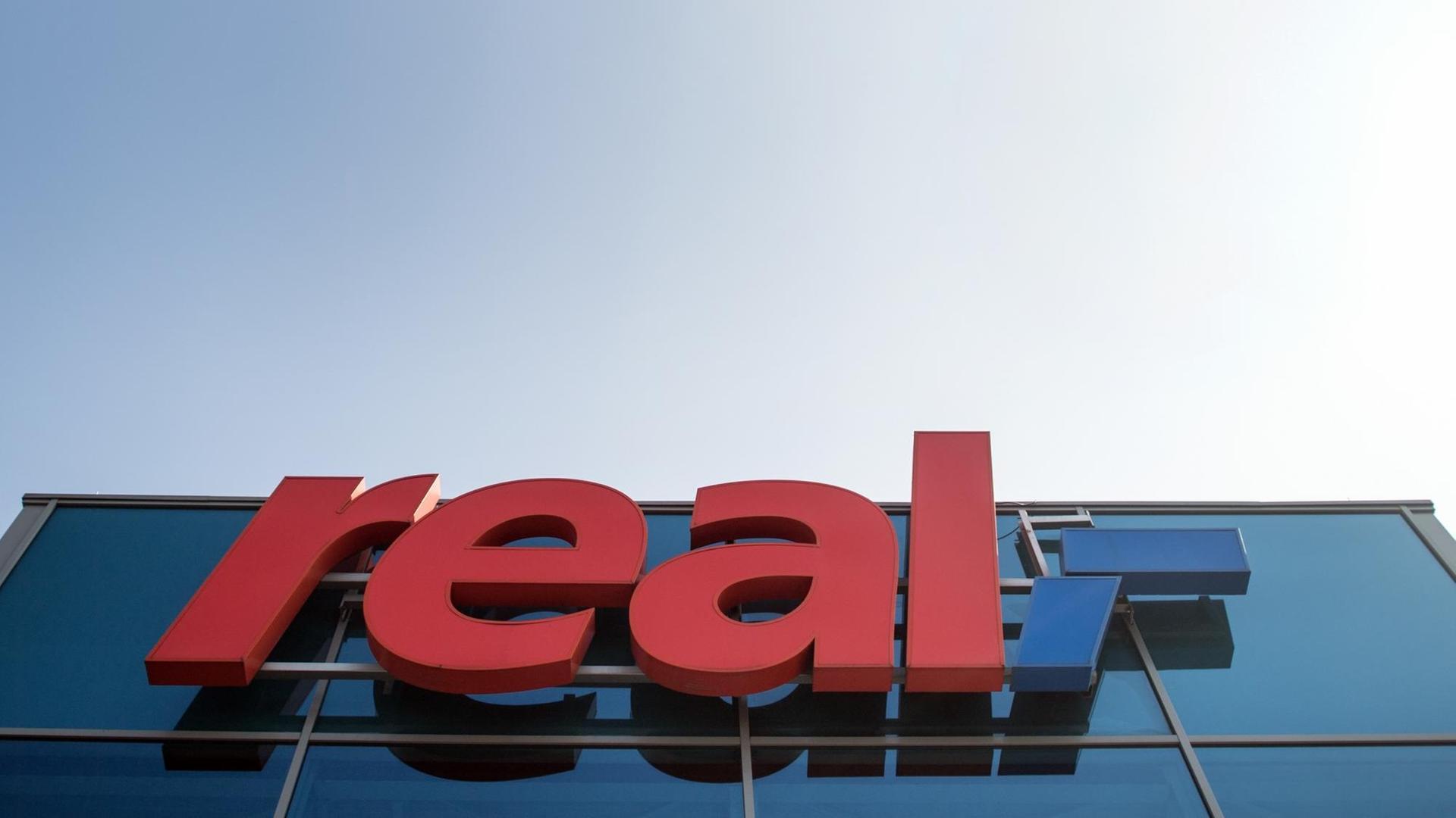 Das Logo von Real hängt an einem Supermarkt. Der Handelskonzern Metro will sich von der Supermarktkette Real trennen