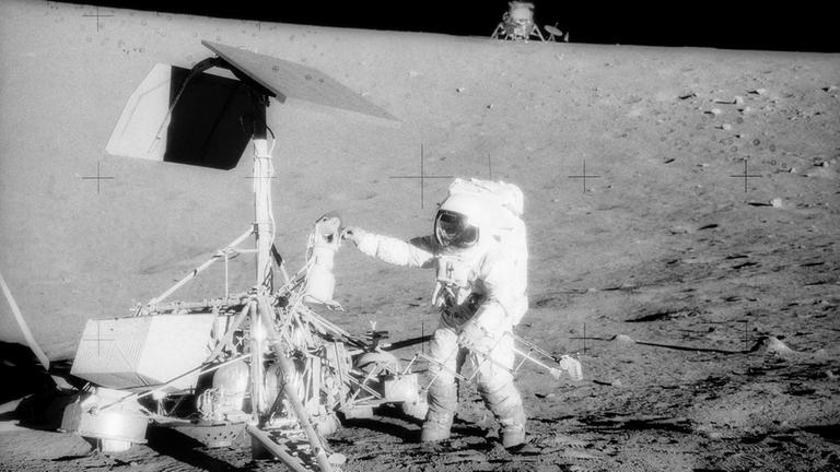 Pete Conrad untersucht Surveyor 3, die Landefähre von Apollo 12 ist am Horizont zu erkennen