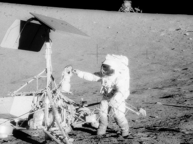Pete Conrad untersucht Surveyor 3, die Landefähre von Apollo 12 ist am Horizont zu erkennen