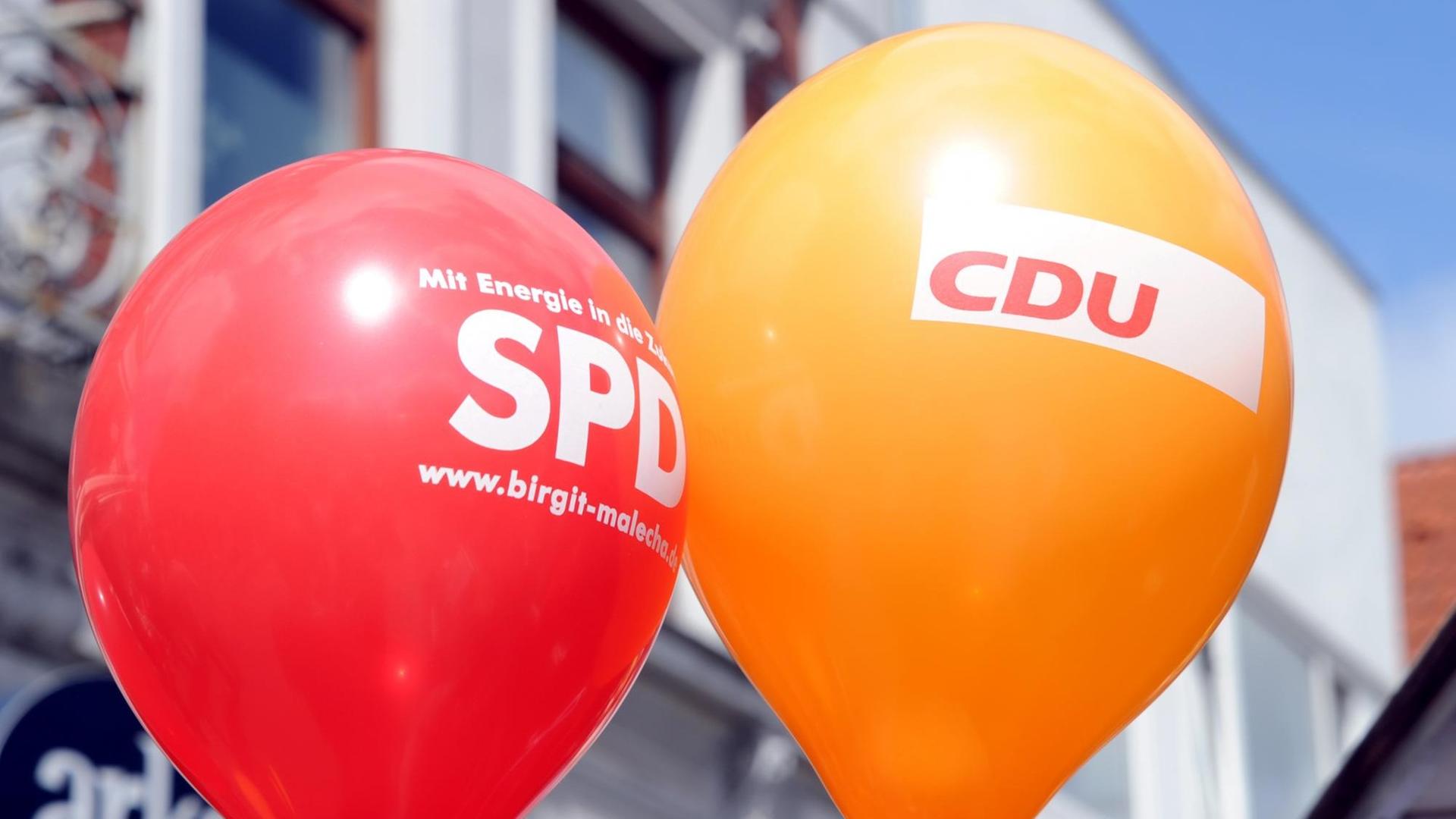 Die Namen der Parteien CDU und CSU auf schwarzem Hintergrund stehen neben dem Namen SPD auf rotem Hintergrund, darüber sind Bremsspuren zu sehen.