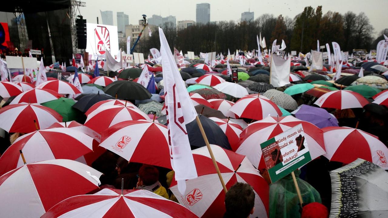 Sie sehen viele rot-weiße Regenschirme von Teilnehmern der Demonstration.
