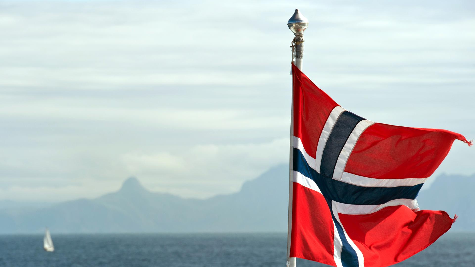 Die Fahne von Norwegen weht im Wind auf einer Fähre unweit der nordnorwegischen Stadt Bodø am Europäischen Nordmeer, aufgenommen am 21.07.2011.