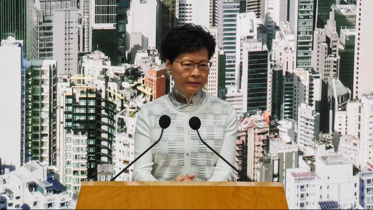 Carrie Lam vor einer Fotowand mit der Skyline von Hongkong.