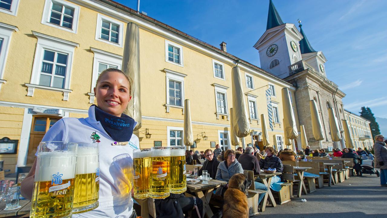 Eine Kellnerin trägt am 12.01.2014 vor dem Herzöglichen Bräustüberl in Tegernsee (Bayern) mehrere Helle zu einem Tisch.