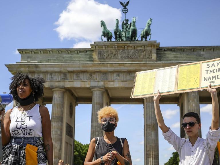 Aktivisten vor dem Brandenburger Tor halten ein Schild mit der Aufschrift "Say Their Names" in die Höhe.