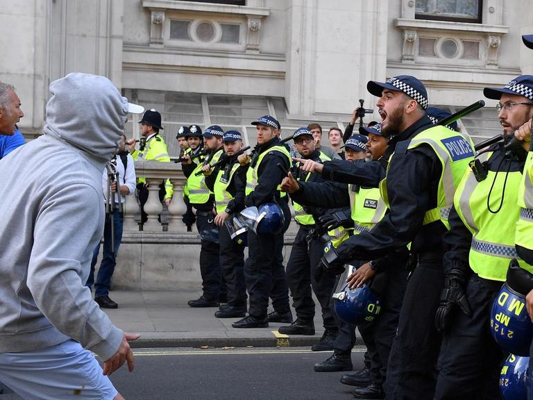 Die Downing Street ist Schauplatz für die Auseinandersetzung von Demonstranten auf der linken Seite und einer Reihe aus Polizisten auf der rechten Seite.