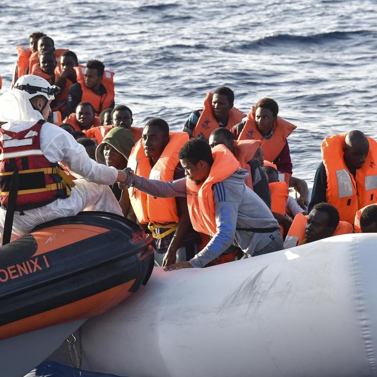 Mitglieder der Maltesischen NGO-Organisation MOAS helfen am 3.11.2016 Flüchtlingen an  Bord eines kleinen Rettungsbootes während einer gemeinsamen Rettungsaktion mit dem Italienischen Roten Kreuz vor der Küste Libyens.