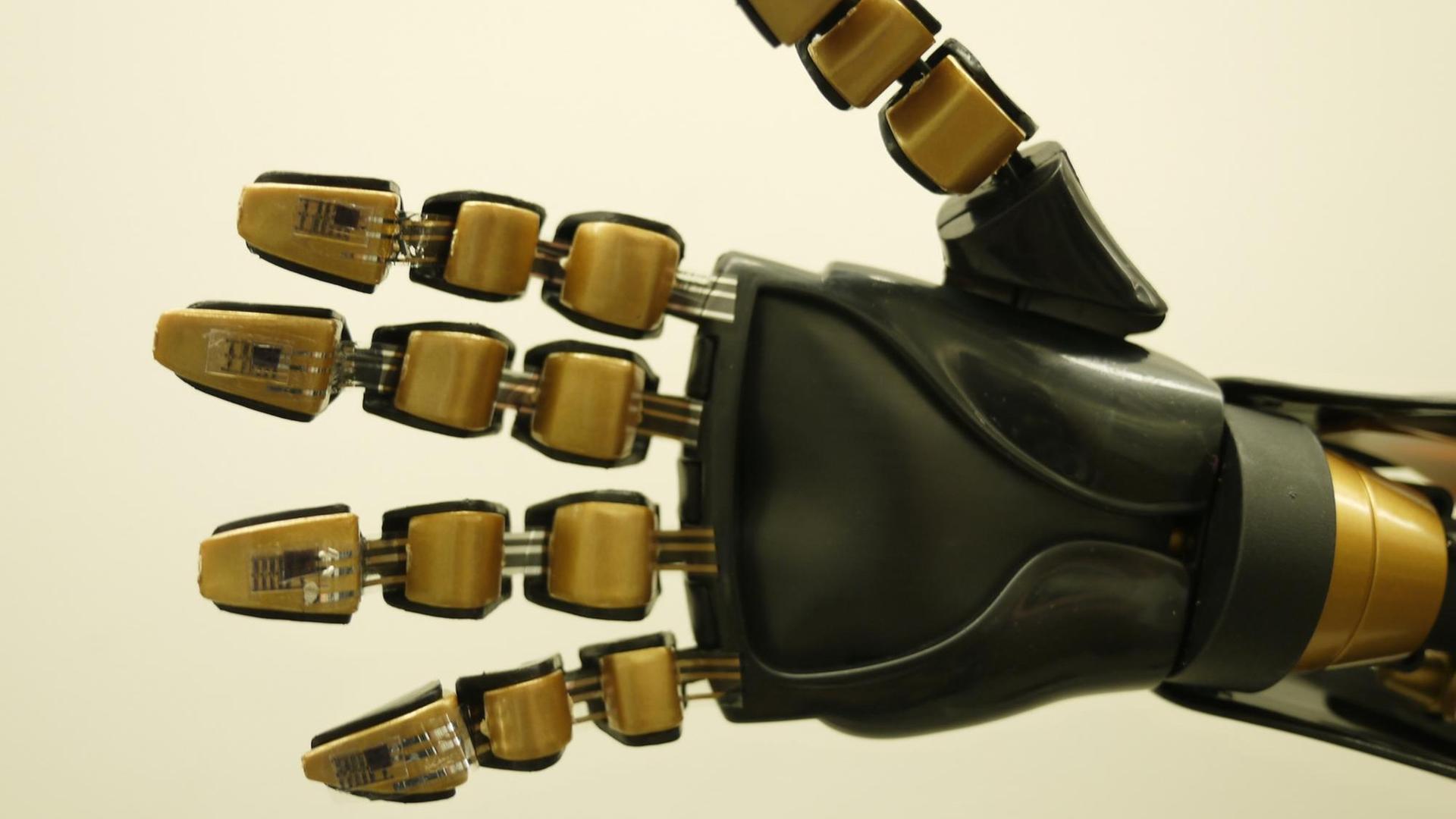 Eine künstliche Hand, bestehend aus mehreren goldfarbenen Elementen und schwarzem Plastik