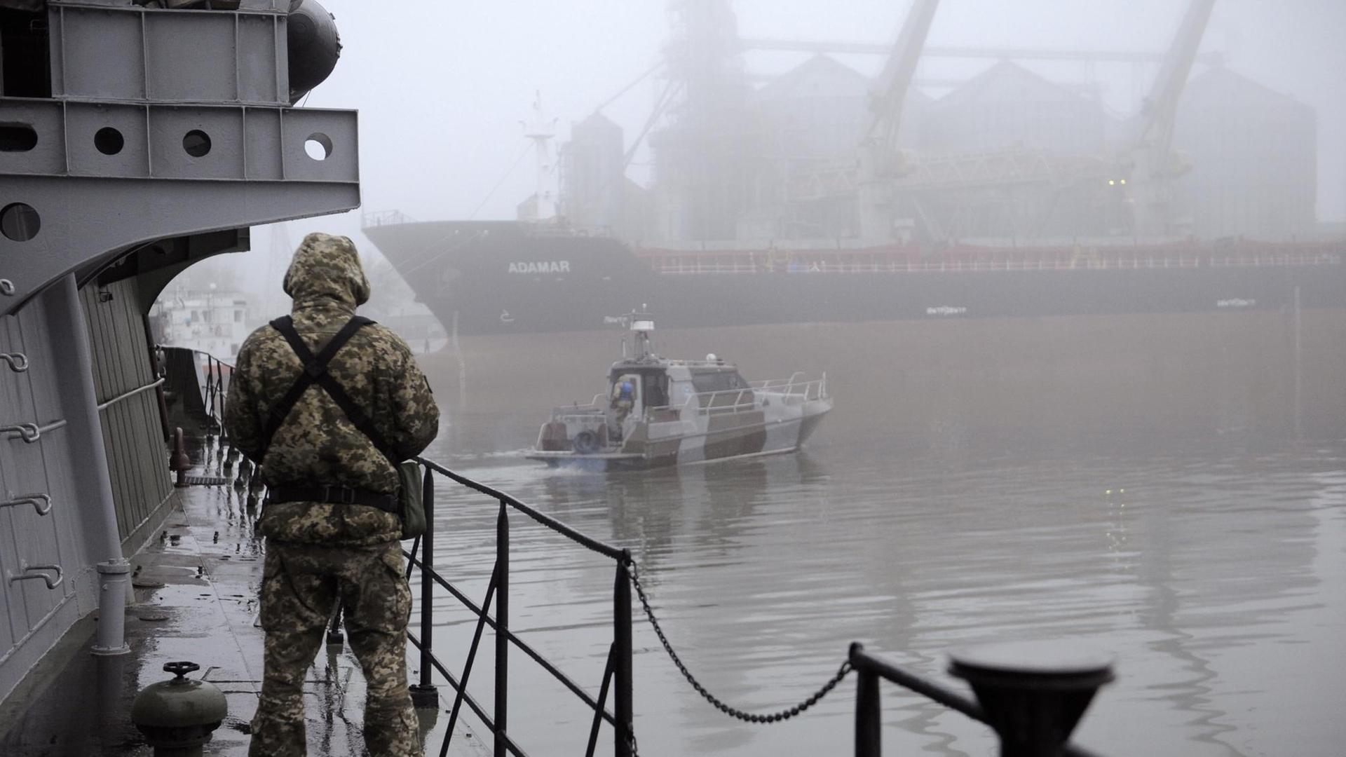 Der Soldat im Tarn-Anzug steht im Hafen auf dem Schiff. 
